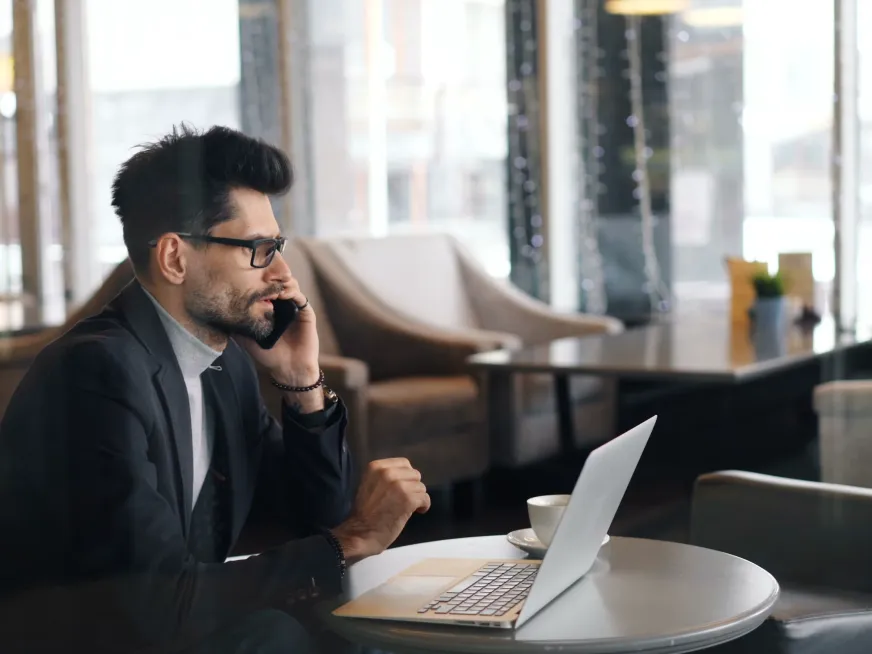 Consultant on a phone call at a laptop in a hotel lounge