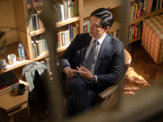 Executive reading in a leather armchair beside a bookcase